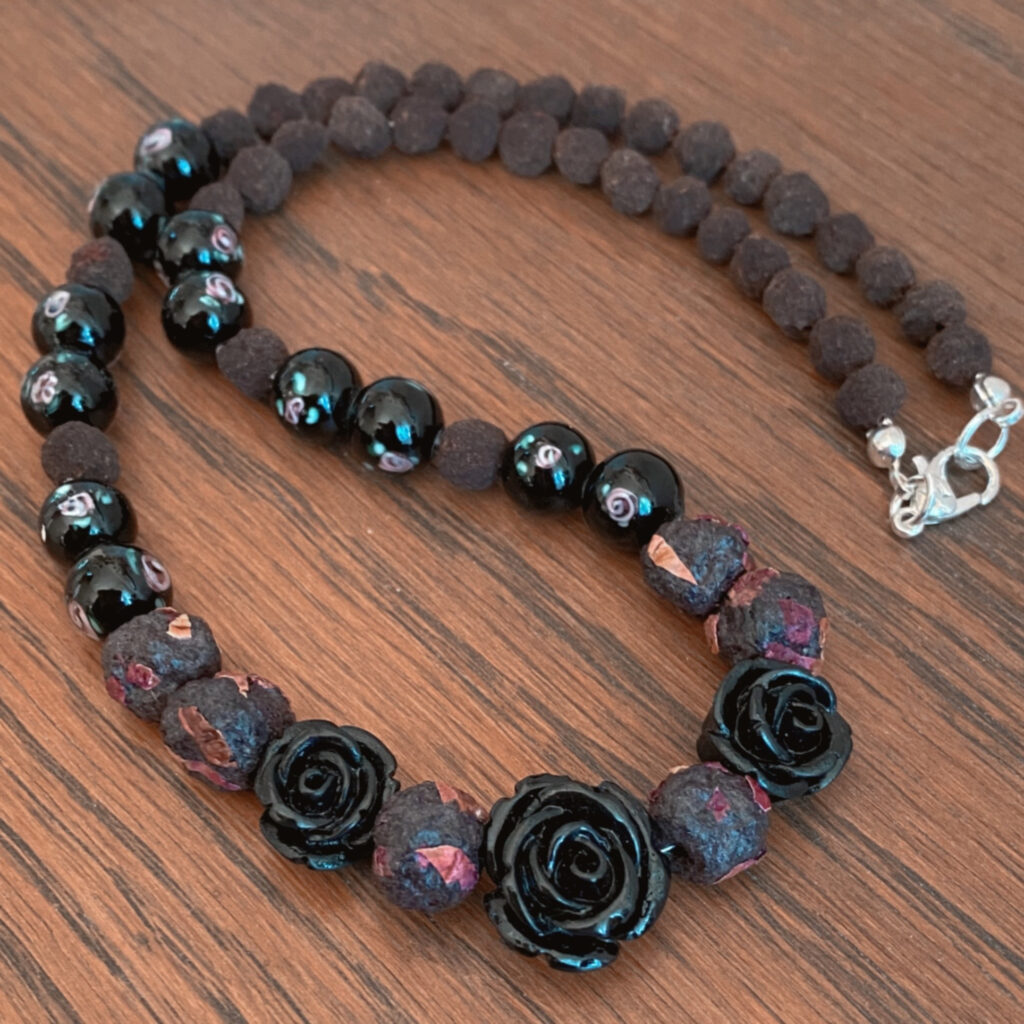 A necklace made from dark red and black rose petal beads